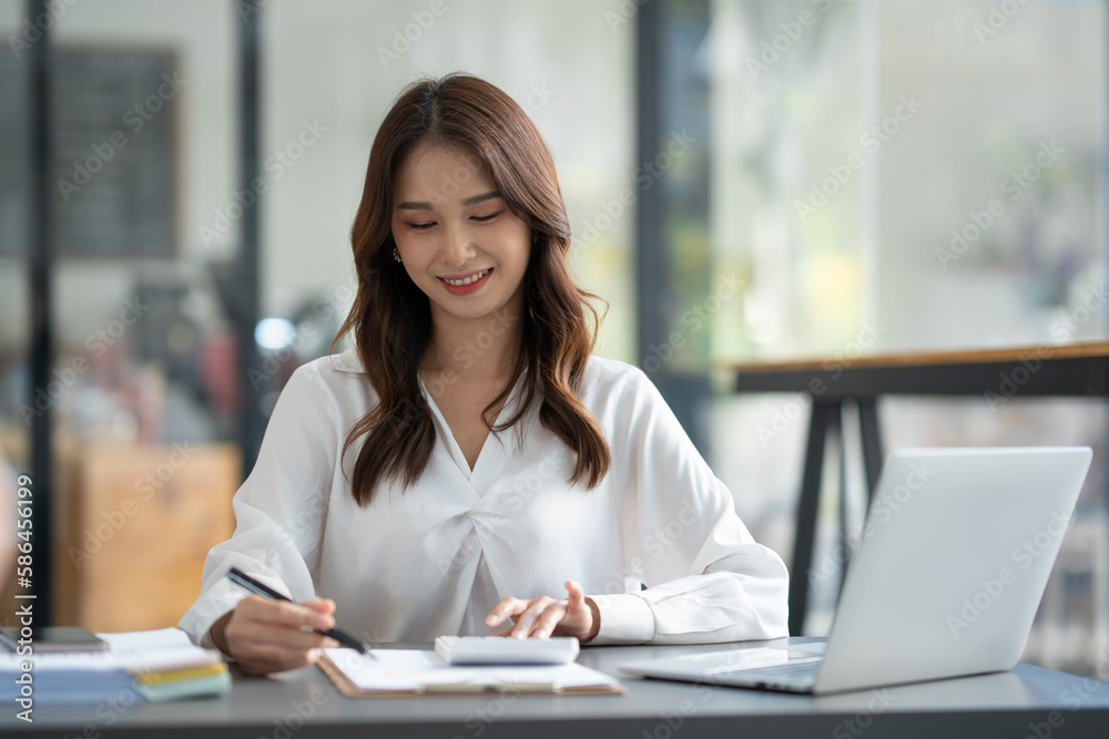 Asian businesswoman sitting in an office looking with graph detail on laptop computer Chart of real estate business growth data in the office. Asian businesswoman sitting in an office looking with graph detail on laptop computer Chart of real estate business growth data in the office.