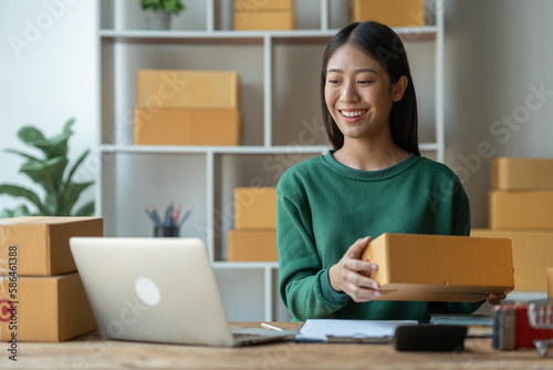 Asian female startup business owner She smiled and was delighted to receive an online order from a customer showing her information on her laptop to prepare parcels for delivery through the company.