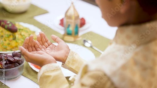 Shoulder shot of muslim kid praying to god during Ramadan festival celebration at home - concept of ramzan feast, believe and tradition photo