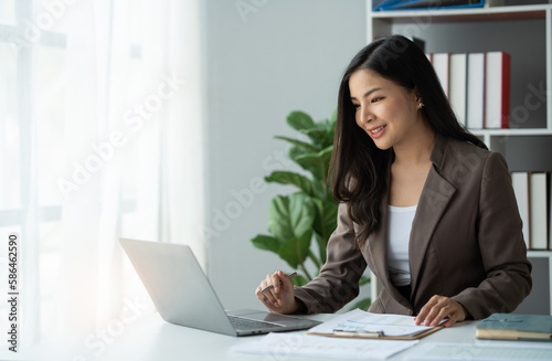 Asian businesswoman  online freelancer  confident investor working at laptop computer and pointing to graph showing financial growth. e-commerce management concept marketing.