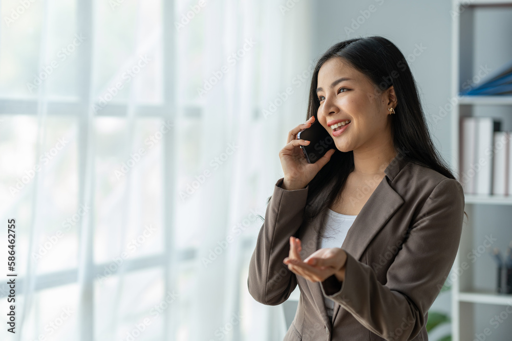 copy space, panorama, banner Asian business woman financially successful entrepreneur professional company executive Wearing a suit standing and talking on the phone in business information. copy space, panorama, banner Asian business woman financially successful entrepreneur professional company executive Wearing a suit standing and talking on the phone in business information.