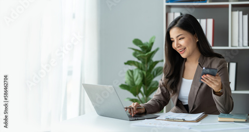 copy space, panorama ,banner ,Smiling beautiful young Asian businesswoman ready to press the phone Talking on the mobile phone in the office with a happy smile. © crizzystudio