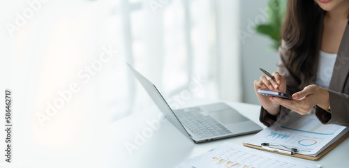 Copy space, Panorama, Banner, Businesswoman holding pen and dialing phone to make contact to client or investor on earnings report, financial income, real estate project in office. photo