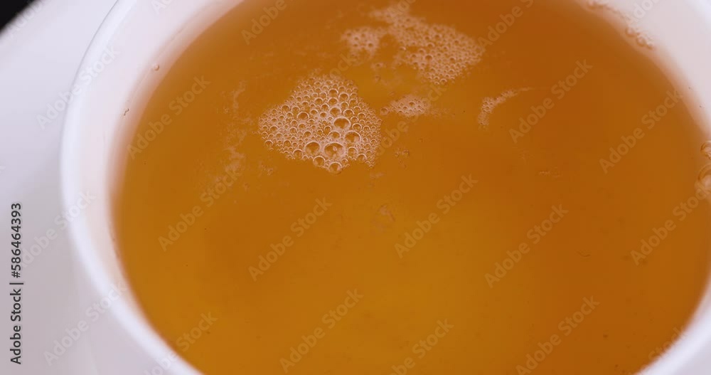 Sugar in hot green tea melts and forms a large number of bubbles, air bubbles from refined sugar in a mug of hot green tea Sugar in hot green tea melts and forms a large number of bubbles, air bubbles from refined sugar in a mug of hot green tea