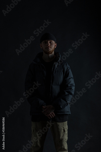 Silhouette of a fashionable guy in trendy clothes with a jacket and a hat in the dark © alones