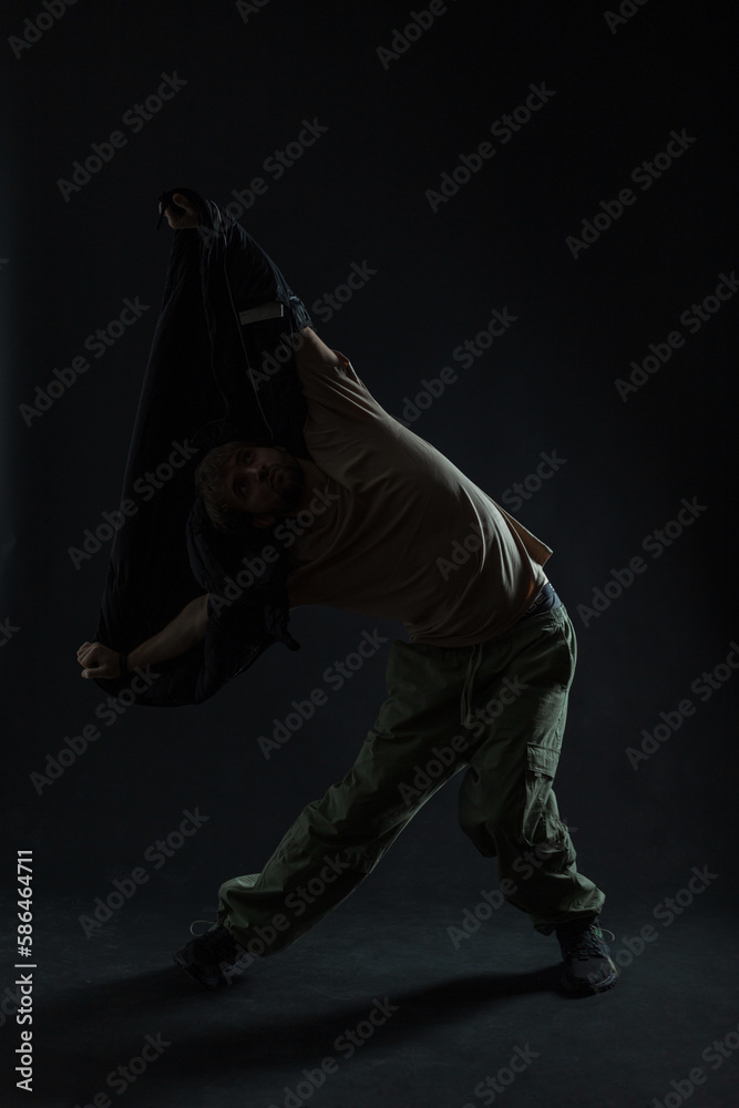 silhouette of handsome professional man dancer in fashion clothes dances in the dark