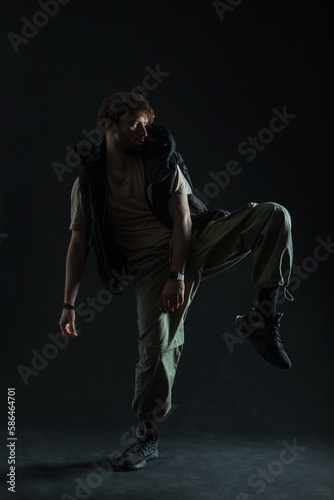 Fototapeta Naklejka Na Ścianę i Meble -  Stylish trendy dancer man in fashion clothes is dancing in the dark. Guy dancer silhouette
