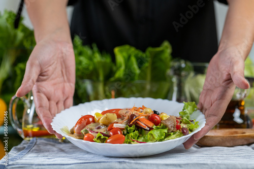 Fototapeta Naklejka Na Ścianę i Meble -  woman chef show mix fresh green baby cos salad and pour salad dressing in glass blow. Organic Vegetables mix all green salad In glass bowl. Breakfast fresh salad and clean vegetable.