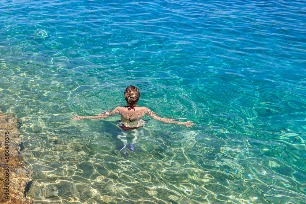 Woman swimming in a blue crystal clear watter