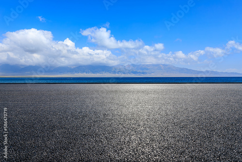 Asphalt road and blue lake with mountain background © ABCDstock
