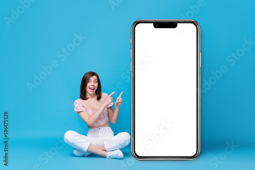 Photo of excited funny lady sit hand direct big telephone demonstrate booking service app empty space isolated on blue color background © deagreez
