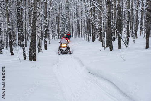 Athletes on a snowmobile moving in the winter forest in the mountains of the Southern Urals