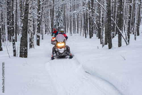 Athletes on a snowmobile moving in the winter forest in the mountains of the Southern Urals