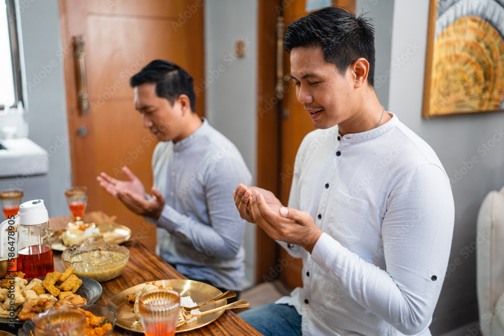 Asian men pray before meals while gathered in the dining room