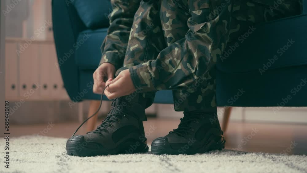 Feet of military woman in army uniform tying shoelaces, preparing for service