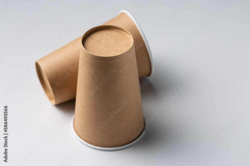 Disposable cardboard biodegradable cups on a white table, gray background. Disposable cardboard biodegradable cups on a white table, gray background.