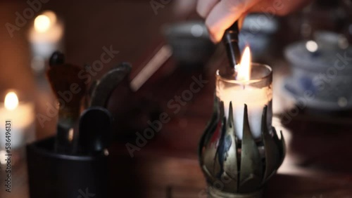 female hand light candles in a candlestick to give a pleasant atmosphere during tea ceremony, close-up photo