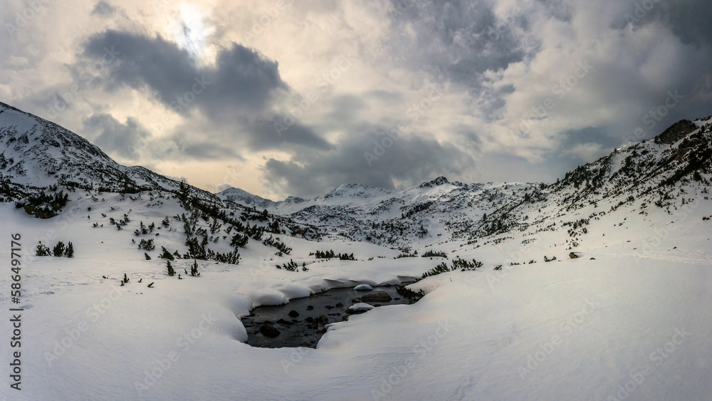 Fototapeta premium Source of the Bunderishka river near Ribno lake in snowy cloudy morning. Winter mountain landscape in Pirin national park, Bulgaria.
