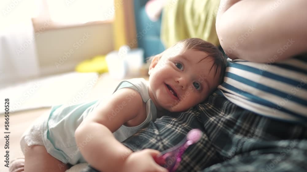 baby cuddles up to mom smiling and looking at the camera. happy family kid dream concept. baby hugs mom's leg and smiles. baby lays her head on mom lifestyle baby cuddles up to mom smiling and looking at the camera. happy family kid dream concept. baby hugs mom's leg and smiles. baby lays her head on mom lifestyle