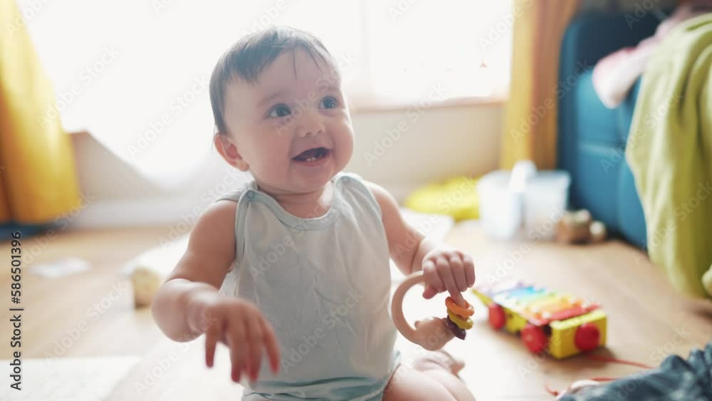 baby play toy on the floor at home. happy family kid dream concept. baby smiling waving his hands in kindergarten. baby holding a toy looking at mom. child play in kindergarten lifestyle baby play toy on the floor at home. happy family kid dream concept. baby smiling waving his hands in kindergarten. baby holding a toy looking at mom. child play in kindergarten lifestyle