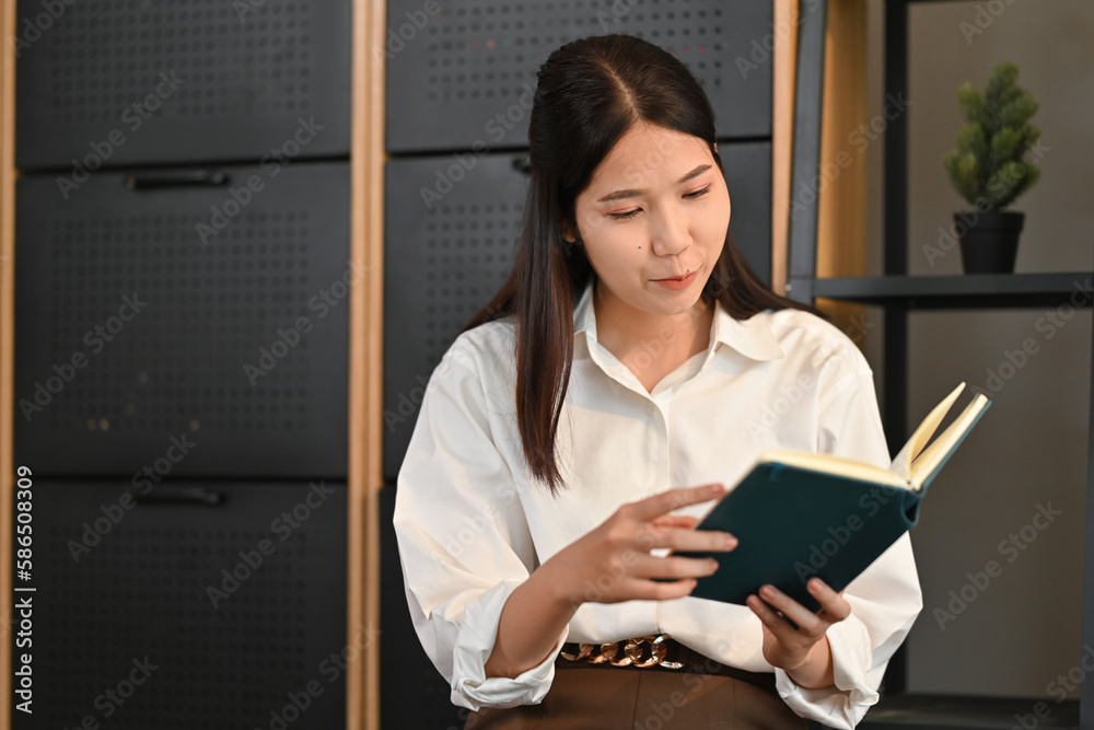Fototapeta premium Relaxed millennial woman reading favorite novel on floor and in living room. People, leisure and lifestyle concept