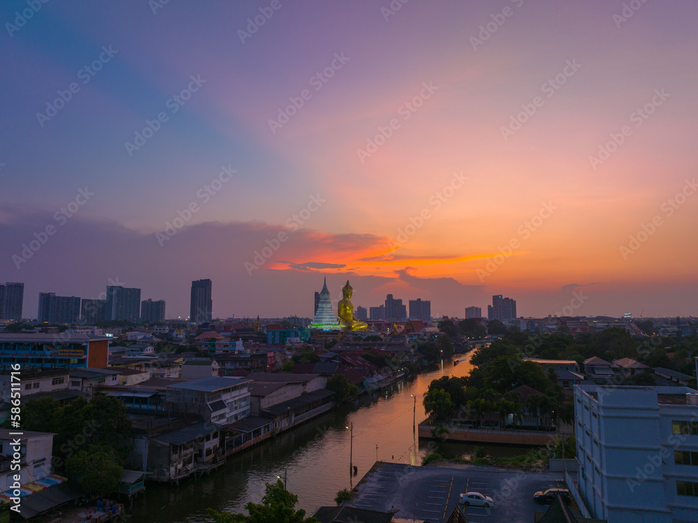Naklejka premium .aerial view golden big Buddha Wat Paknam Phasi Charoen in sunset. .beautiful sunset reflection on a canal in front big buddha. .scenery sky in twilight background.the one famous landmarks