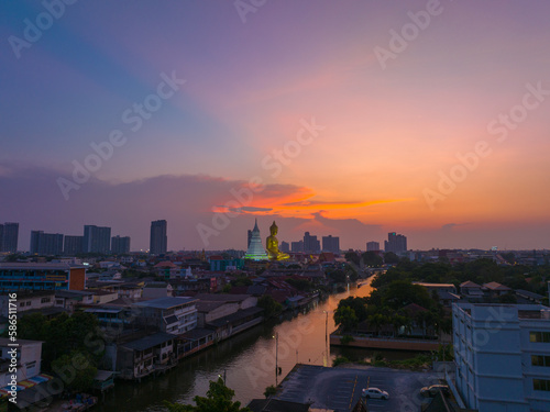 .aerial view golden big Buddha Wat Paknam Phasi Charoen in sunset. .beautiful sunset reflection on a canal in front big buddha. .scenery sky in twilight background.the one famous landmarks