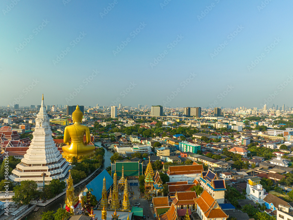 Fototapeta premium .aerial view golden big Buddha Wat Paknam Phasi Charoen in sunset. .beautiful sunset reflection on a canal in front big buddha. .scenery sky in twilight background.the one famous landmarks 