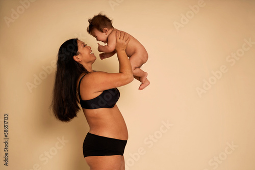 Asian woman in underwear holding a toddler above head photo