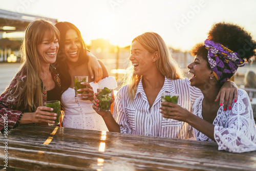 Happy girls having fun drinking cocktails at bar on the beach - Soft focus on center girl face photo