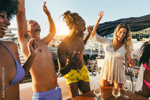 Happy multiracial friends having fun dancing together at boat party outdoor - Soft focus on african man head