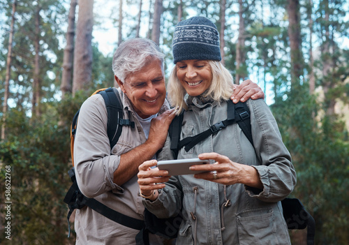 Phone, hiking and happy senior people in nature with network, social media or video streaming in forest. Mature couple of friends trekking or travel in woods with funny meme, smartphone or mobile app
