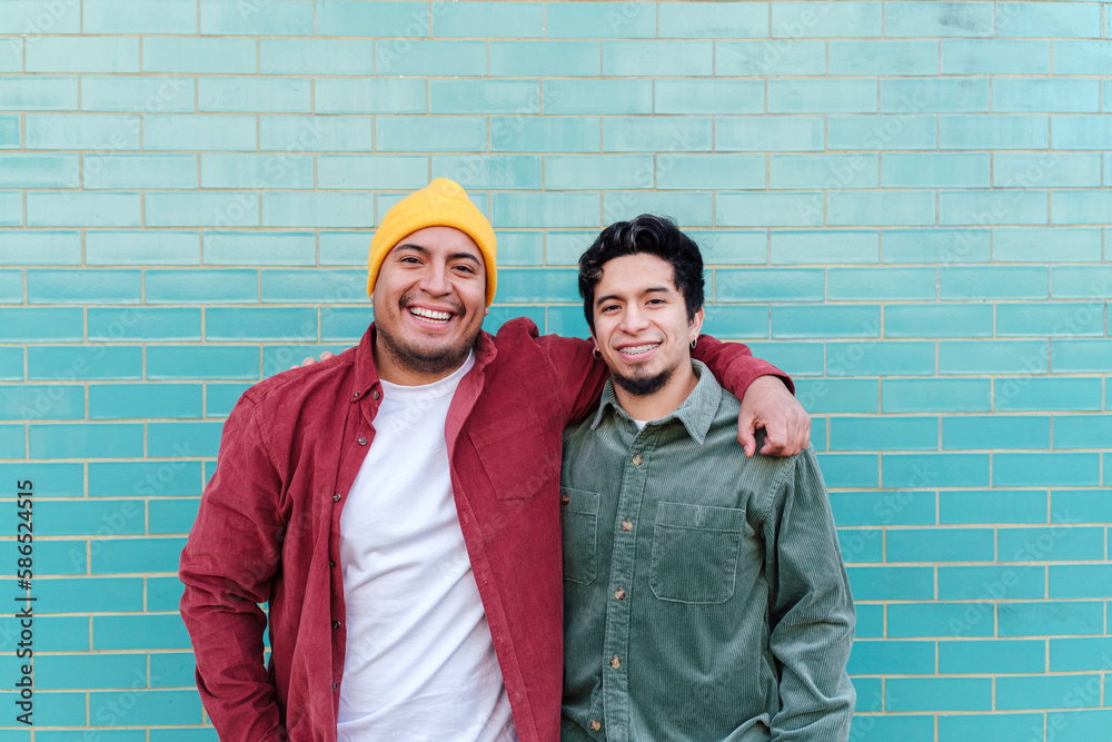 © VISTA by Westend61 - Smiling man with brother standing in front of turquoise brick wall © VISTA by Westend61 - Smiling man with brother standing in front of turquoise brick wall
