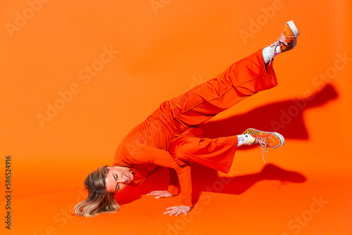 Woman breakdancing against orange background photo