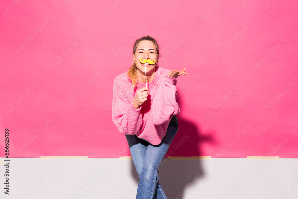 Woman having fun with fake mustache against pink background Woman having fun with fake mustache against pink background