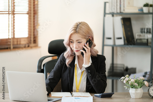 Close up on laptop in office, Asian happy beautiful businesswoman in formal suit work in workplace. Attractive female employee office worker smile. © Treerat