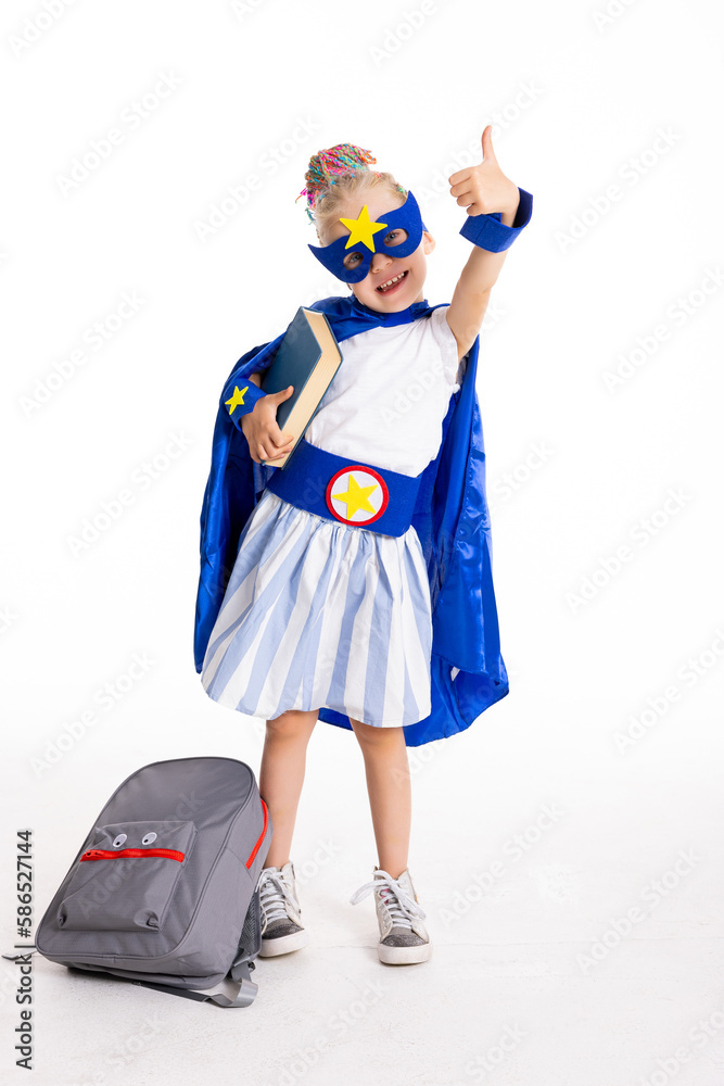 Pre schooler daughte in super hero costume standing on white background holding book and grey backpack ready to school concept. Pre schooler daughte in super hero costume standing on white background holding book and grey backpack ready to school concept.