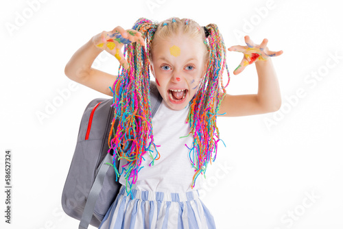 Modern small school girl stands on white background isolated holding backpack looking at camera posing in stylisg clothes laughing back to school concept.