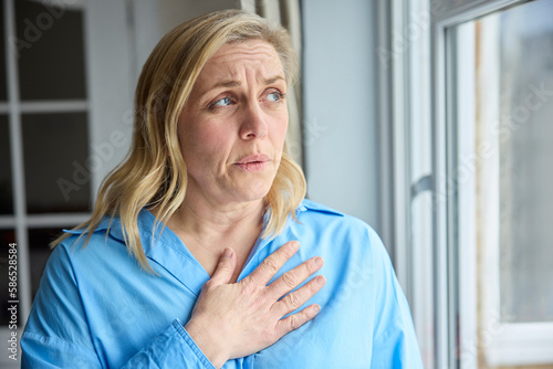 Menopausal Mature Woman At Home Standing By Window Suffering With Heart Palpitations photo