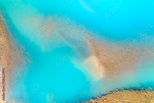 Clear azure water in a mountain lake. The shore with stones. View of the water from a drone. Landscape from the air. Natural landscape as wallpaper.