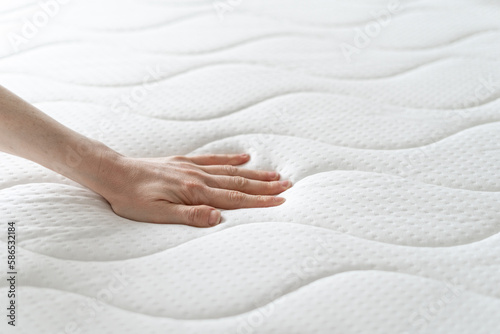 woman press on comfortable mattress and checking quality