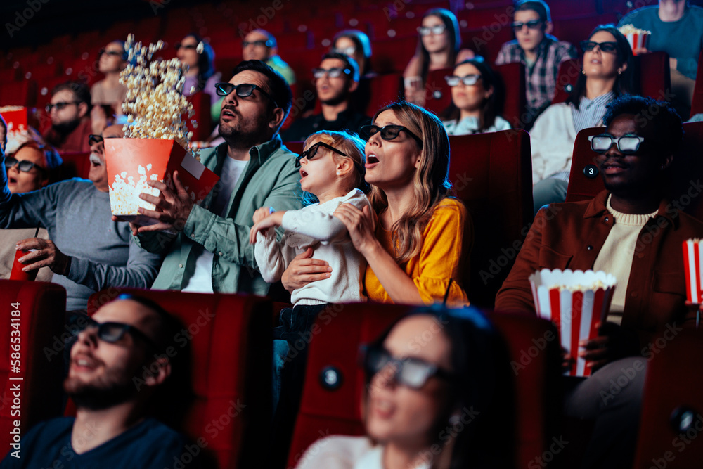 Audience jumping in fear in movie theater.