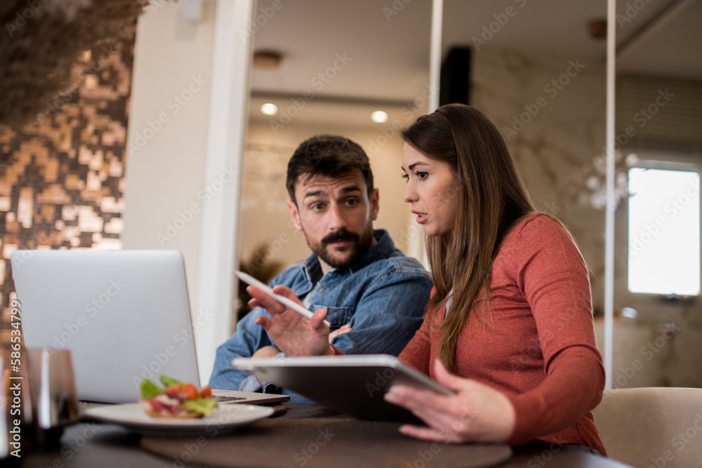 A couple enjoying a quiet morning at home, with breakfast and technology in hand. A couple enjoying a quiet morning at home, with breakfast and technology in hand.