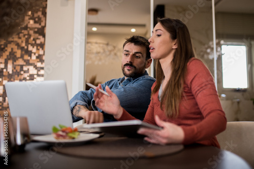Young freelancer couple working from home over breakfast.