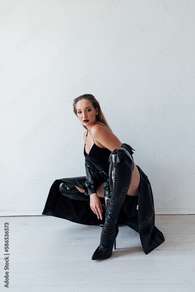 a woman in a leather cloak and black clothes sits on a white background a woman in a leather cloak and black clothes sits on a white background