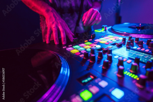 Close up of DJ hands on dj console mixer during concert in the club