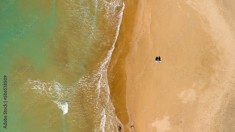 Perpendicular aerial view on a coast of the mediterranean sea, in Italy. The beach is sandy. Two people in love walk on the shoreline. Perpendicular aerial view on a coast of the mediterranean sea, in Italy. The beach is sandy. Two people in love walk on the shoreline.