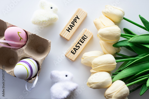 Colorful decorative eggs and HAPPY EASTER text close-up, against the background of a white rabbit