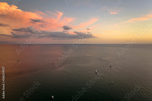 Aerial view of small yachts at sunset floating on sea waves with ripple surface. Motor boats recreation on ocean surface