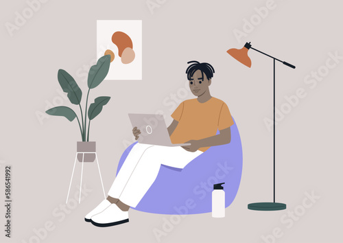 an African hipster character sits on a bean bag while typing on their laptop in their home office